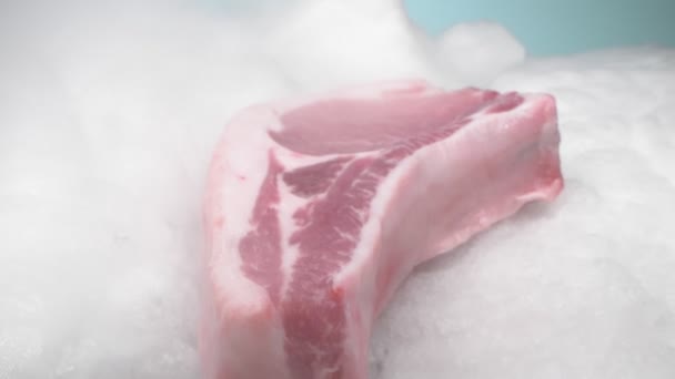 Extreem close-up, gedetailleerd. varkensvlees steak op het bot op ijs met dikke witte rook — Stockvideo