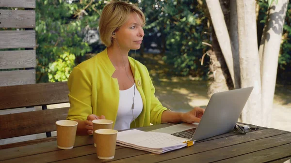 Femme accro au travail travaillant sur ordinateur portable dans un café à l'extérieur avec trois tasses de café — Photo