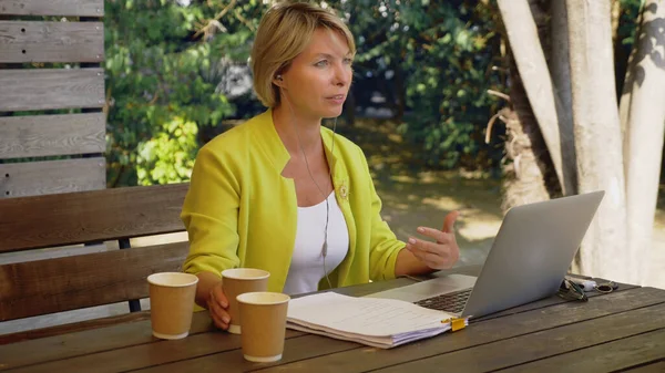 İşkolik bir kadın dışarıda, kafede dizüstü bilgisayarda üç fincan kahveyle çalışıyor. — Stok fotoğraf