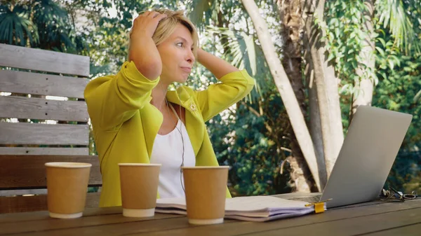 Workoholik žena pracující na notebooku v kavárně venku se třemi šálky kávy — Stock fotografie