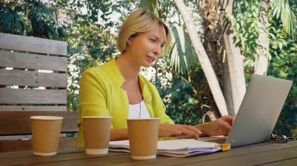 İşkolik bir kadın dışarıda, kafede dizüstü bilgisayarda üç fincan kahveyle çalışıyor. — Stok fotoğraf