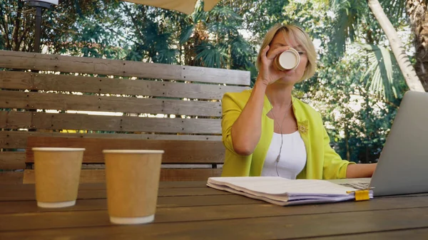 Workaholic vrouw werken op laptop in cafe buiten met drie koppen koffie — Stockfoto