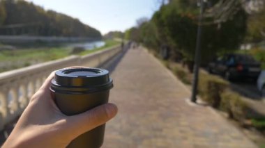  Bir adam elindeki tek kullanımlık kahveyi tutar ve sokakta yürür.