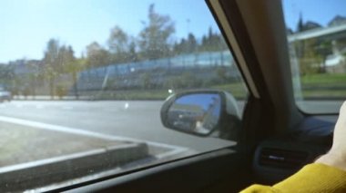 Şehirde araba süren bir adamın birinci şahıs görüntüsü. Güneş parlıyor