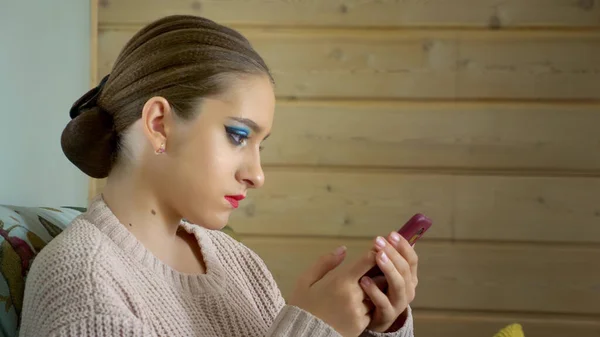 Een danseres met een heldere make-up gebruikt de telefoon tijdens een pauze — Stockfoto