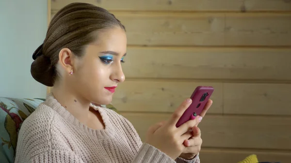 Dívka tanečnice s jasným make-upem používá telefon během přestávky — Stock fotografie