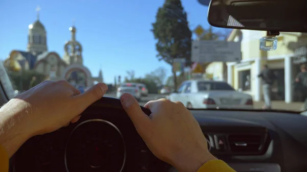 Vista in prima persona di un uomo che guida un'auto in movimento per la città. bagliore del sole — Foto Stock