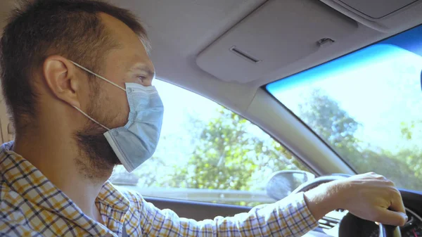 Ein junger Mann mit medizinischer Maske fährt Auto. vertikal — Stockfoto