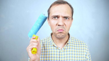 Elinde boya silindiri olan üzgün bir gencin portresi.