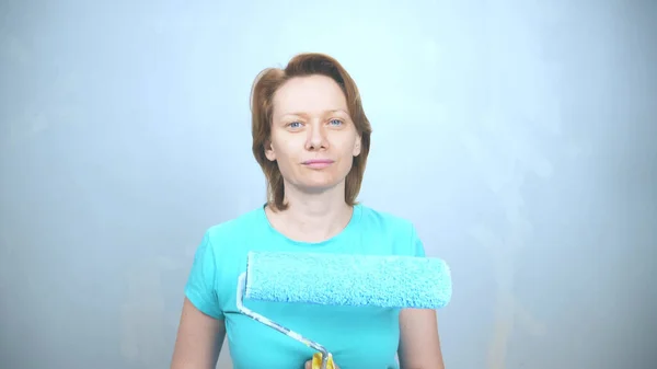 Retrato de uma menina com um rolo para pintar as paredes olhando para a câmera — Fotografia de Stock