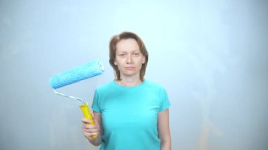 Duvarları boyamak için silindirli yorgun bir kızın portresi.