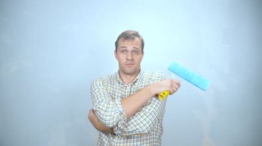 Elinde boya silindiri olan üzgün bir gencin portresi.