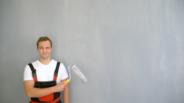 Espaço para cópia. retrato de um homem bonito com um rolo para pintar as paredes — Vídeo de Stock