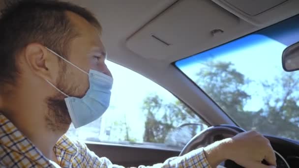 Ein junger Mann mit medizinischer Maske fährt Auto. vertikal — Stockvideo