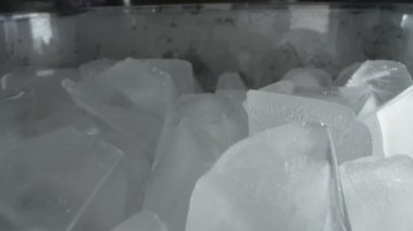 Son derece yakın plan, detaylı. Plastik şeffaf bir kabın içindeki buz küpleri