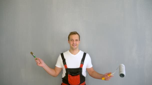 복사 공간. 벽에 페인트를 칠하기 위해 롤러를 타고 있는 잘생긴 남자의 모습 — 비디오