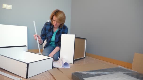 Žena sbírá nábytek, zatímco sedí doma na podlaze, kopírovat prostor — Stock video