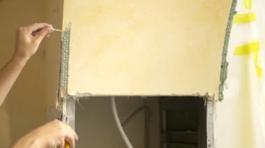 Ev geliştirme. Bir adam bir odada alçıpan kemerini söker.