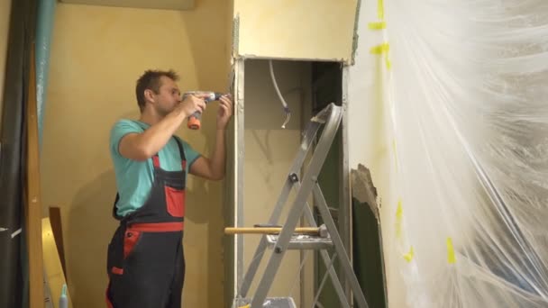 Улучшения дома. мужчина разбирает арку гипсокартона в комнате — стоковое видео