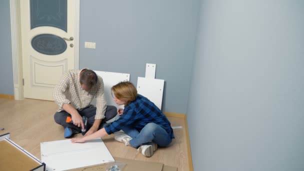 Ehepaar Mann und Frau bauen gemeinsam Möbel in ihrer Wohnung auf. — Stockvideo