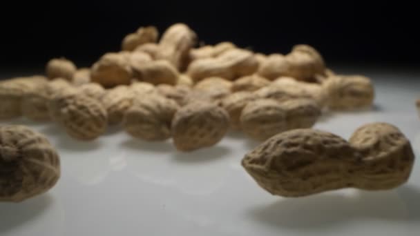 Extremadamente cerca, detallado. cacahuetes con conchas sobre un fondo oscuro — Vídeos de Stock