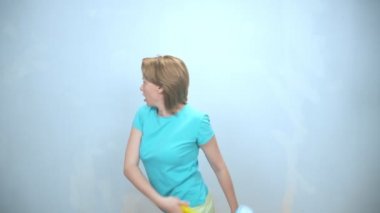 Duvarları boyamak için tekerlekli sandalyesi olan neşeli bir kadın duvarı boyuyor. Boşluğu kopyala