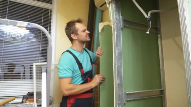 Улучшения дома. мужчина разбирает арку гипсокартона в комнате — стоковое видео