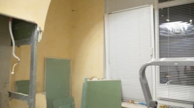 Ev geliştirme. Bir adam bir odada alçıpan kemerini söker.