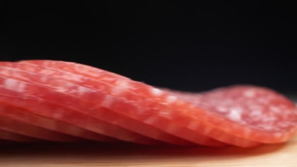 Primer plano extremo, detallado. salchicha de salami cortada en trozos finos en una tabla de madera — Vídeos de Stock