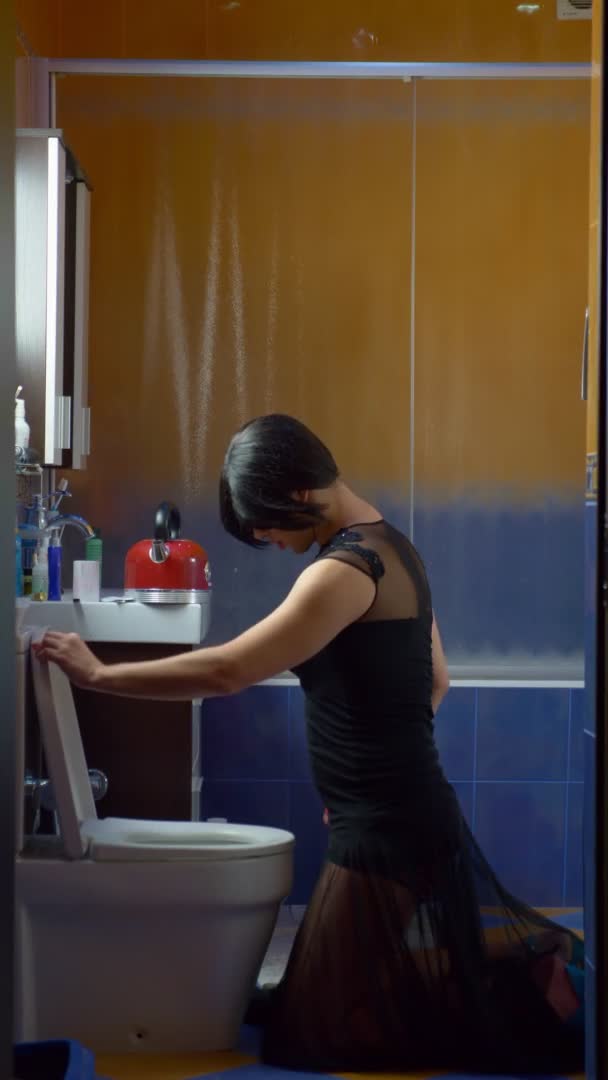 Verticaal. een man vermomd als een vrouw die noedels eet uit het toilet — Stockvideo