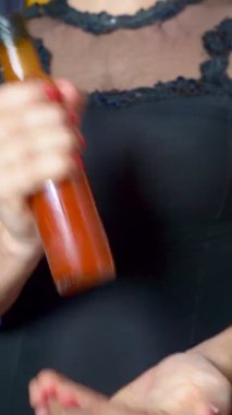 Kadın kılığına girmiş bir adam kırmızı sos şişesini sallıyor.