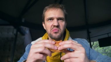 Fast food kafede hamburger yiyen kızgın bir adamın portresi.