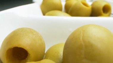 Yakın plan, detaylı. Beyaz tabakta yeşil zeytin.