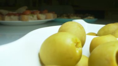 Yakın plan, detaylı. Beyaz tabakta yeşil zeytin.