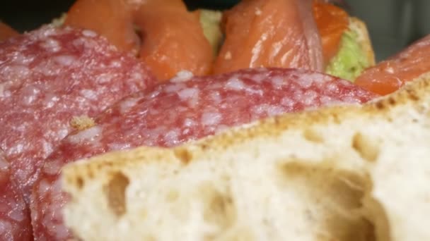 Extrémní detailní záběr. sendviče s rybami a klobásou na talíři — Stock video