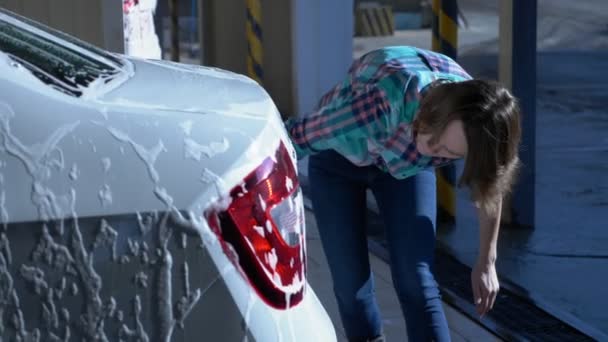 Ung kvinna tvättar en bil vid en självbetjäning biltvätt. övergripande plan — Stockvideo