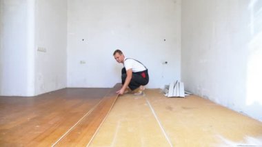 Tulum giyen bir adam, eski bir apartman dairesinin döşemesini söker.