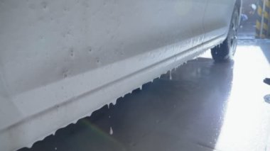 Araba yıkama yerindeki arabadan kalın beyaz köpük damlıyor.