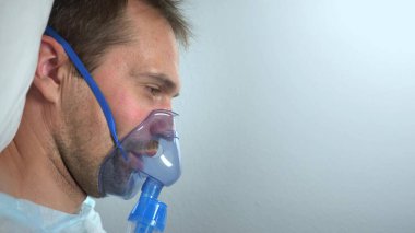 Hastanede bir yatakta yatan oksijen maskeli bir adamın portresi.