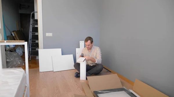 Homem bonito recolhe móveis em casa no quarto. espaço de cópia — Fotografia de Stock