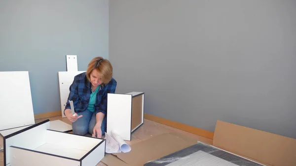 Frau sammelt Möbel, während sie zu Hause auf dem Boden sitzt, kopiert Raum — Stockfoto