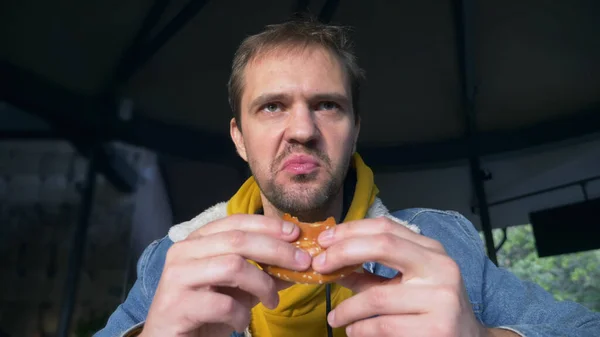 Portrait of angry man eating hamburger at fast food cafe — Stock Photo, Image