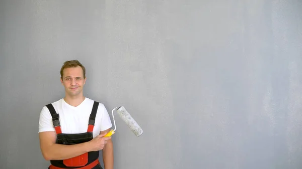 Begrepen, ruimte. portret van een knappe man met een roller om de muren te schilderen — Stockfoto