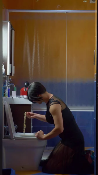 Vertikal. ein als Frau verkleideter Mann isst Nudeln von der Toilette — Stockfoto