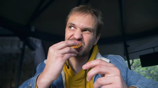 ファーストフードカフェでハンバーガーを食べる怒れる男の肖像画 ストック写真