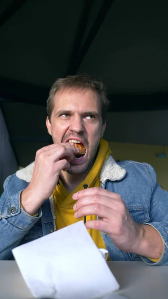 Portret wściekłego człowieka jedzącego hamburgera w fast food cafe Zdjęcia Stockowe bez tantiem