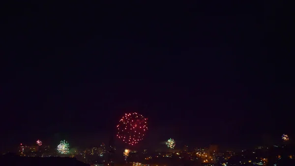 Muchos destellos de fuegos artificiales sobre la ciudad nocturna. vacaciones generales — Foto de Stock