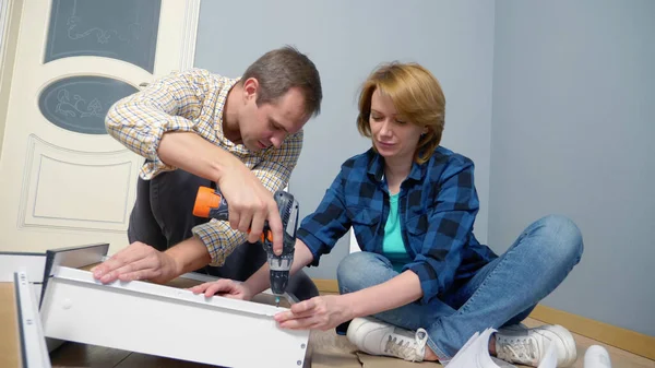 Paar man en vrouw samen installeren meubels in hun appartement. — Stockfoto