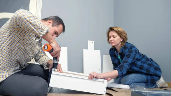 Casal homem e mulher juntos instalar móveis em seu apartamento. — Fotografia de Stock