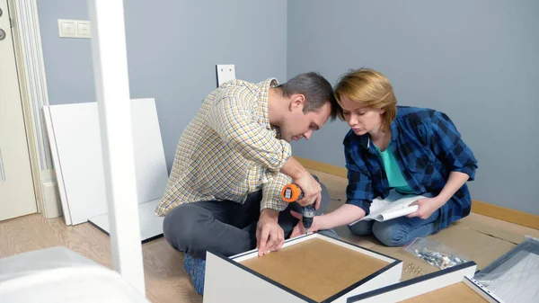 Paar man en vrouw samen installeren meubels in hun appartement. — Stockfoto